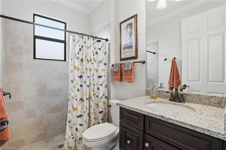 Bathroom with vanity, ornamental molding, and a shower stall