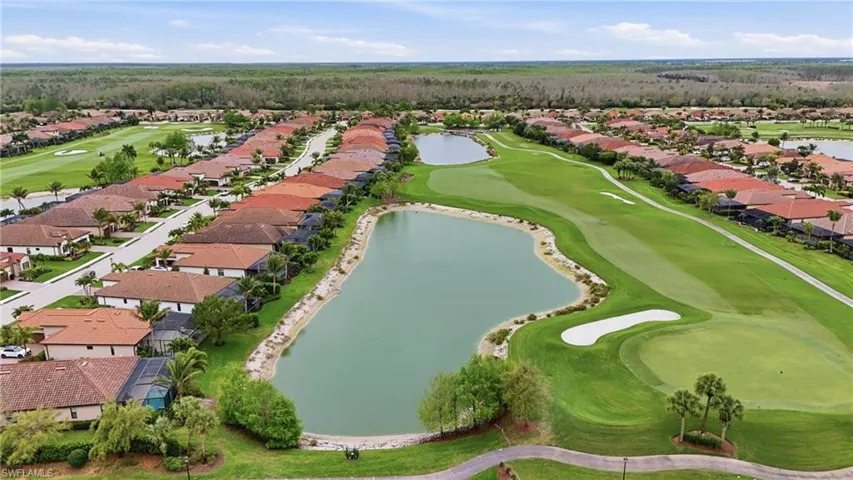 Aerial view of residential area featuring a golf club and a nearby body of water