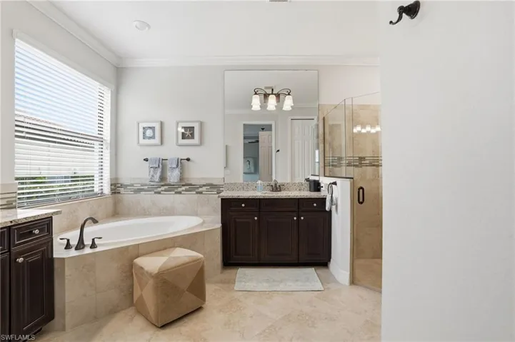 Full bath with vanity, a shower stall, a bath, and crown molding