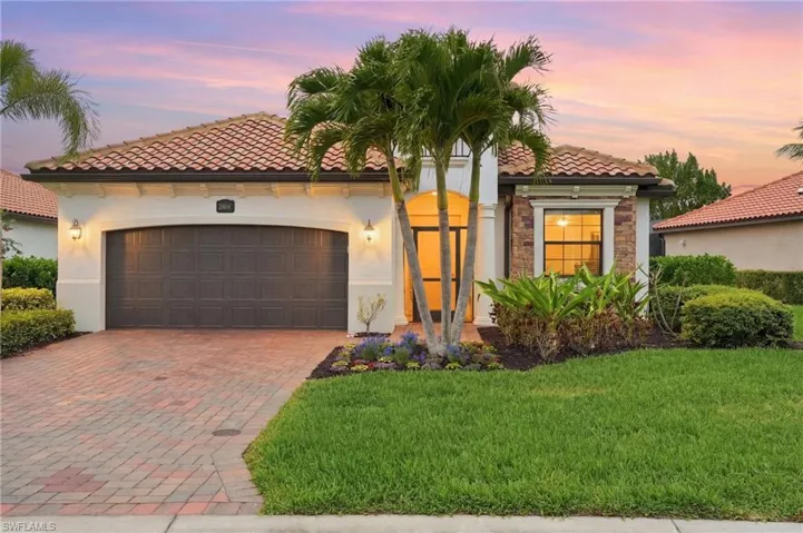 Mediterranean / spanish home featuring decorative driveway, an attached garage, a front lawn, a tile roof, and stucco siding