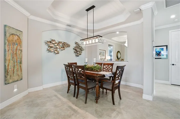 Dining room featuring ornamental molding, a tray ceiling, and arched walkways