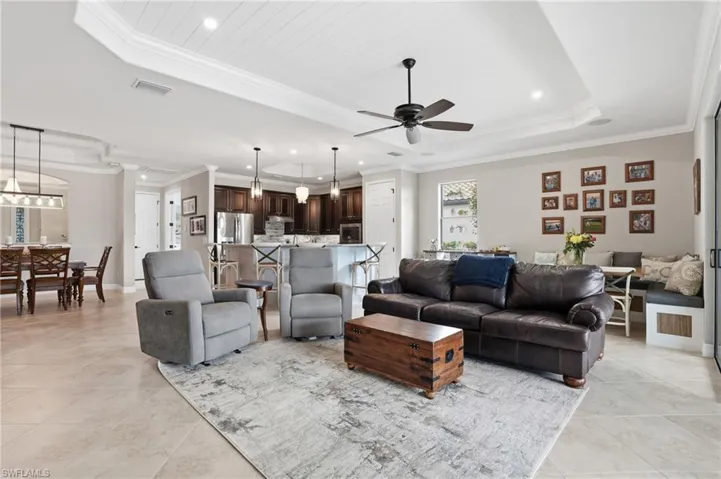 Living room featuring ceiling fan, ornamental molding, a raised ceiling, and recessed lighting