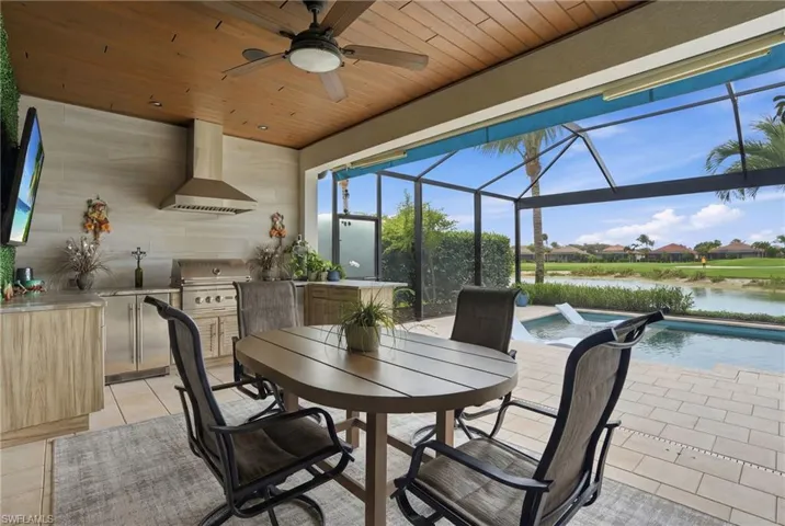 View of patio / terrace with an outdoor kitchen / dining area, an outdoor pool, a residential view, glass enclosure, and a ceiling fan