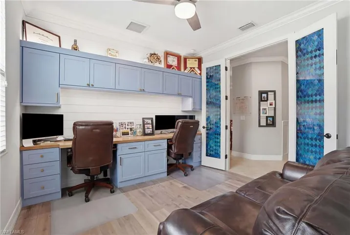 Office area featuring built in desk, crown molding, a ceiling fan, and light wood-style floors