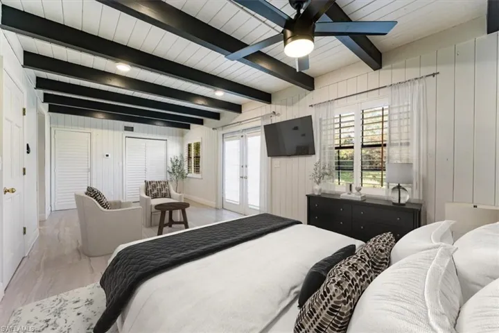 Bedroom featuring french doors, wood walls, light wood-style flooring, access to exterior, and ceiling fan