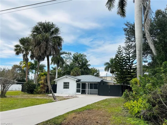 Ranch-style home featuring a sunroom, a metal roof, concrete driveway, and a gate