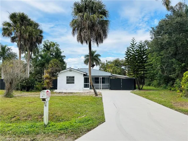 View of front of property featuring a front yard, driveway, a carport, and a metal roof