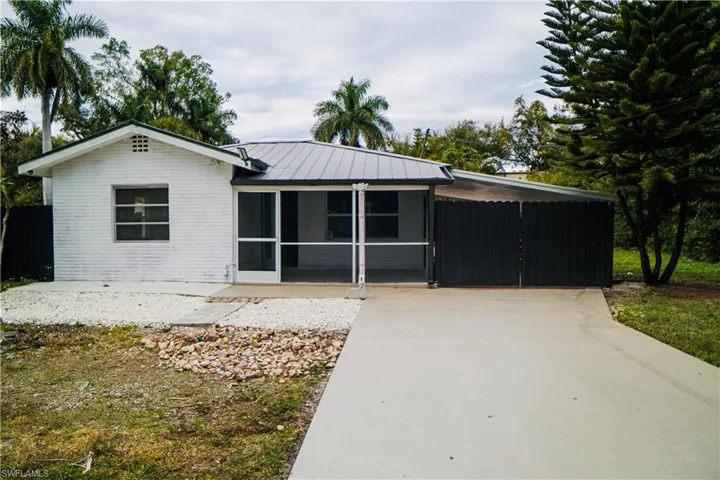 Ranch-style house featuring a standing seam roof, a metal roof, a sunroom, brick siding, and concrete driveway