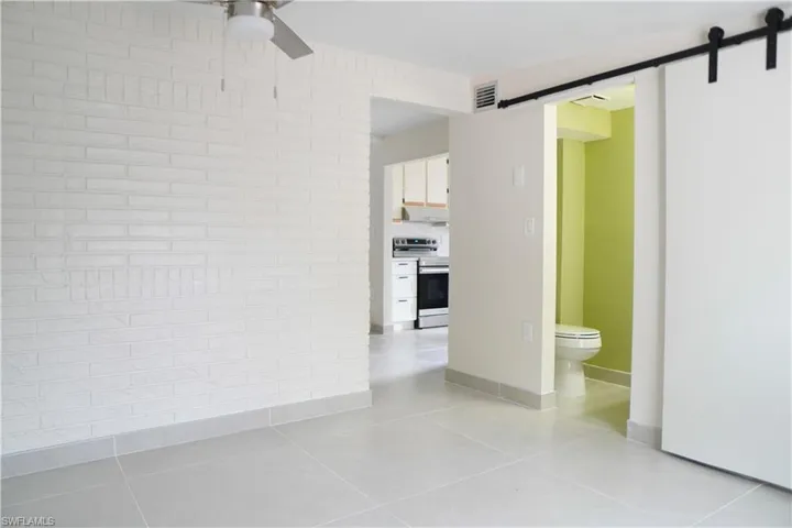 Spare room featuring a barn door, a ceiling fan, and light tile patterned floors