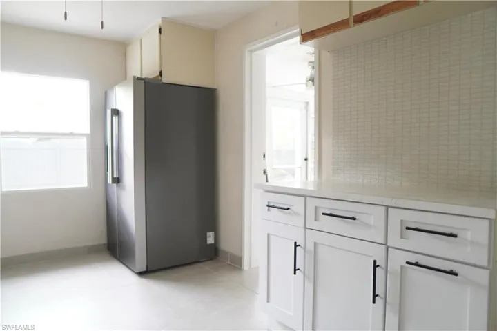 Kitchen featuring freestanding refrigerator, light tile patterned floors, and white cabinets