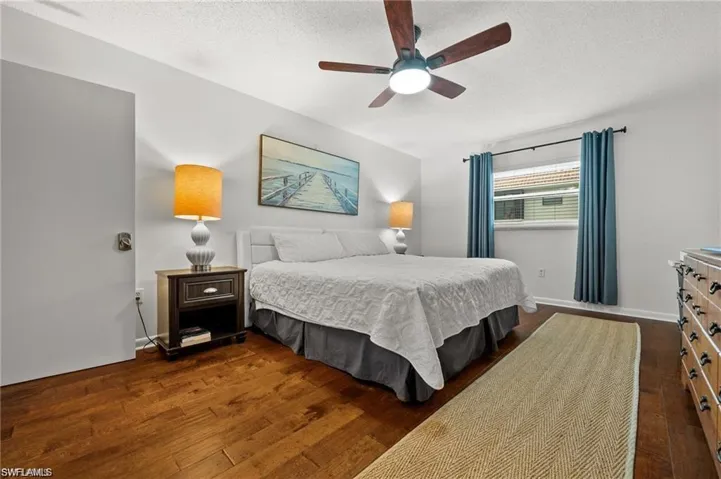 Bedroom with dark wood-type flooring, ceiling fan, and a textured ceiling