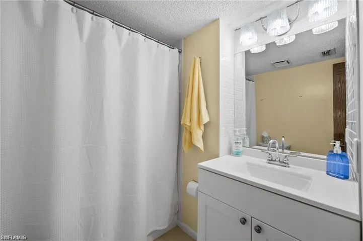 Full bathroom featuring curtained shower, vanity, and a textured ceiling