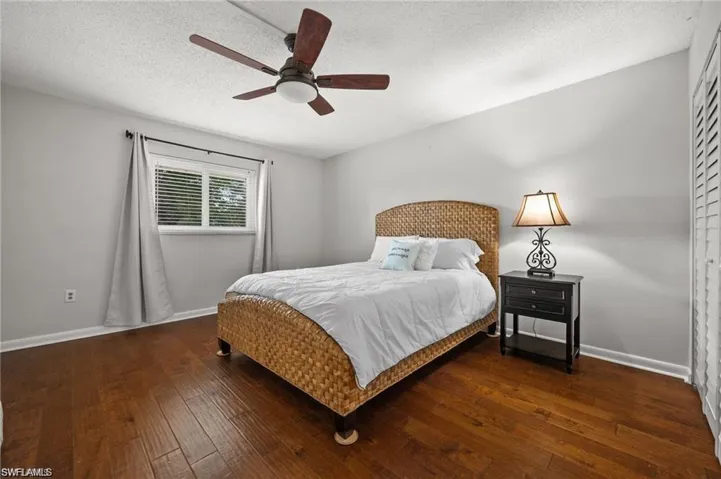 Bedroom featuring dark wood-style floors, a textured ceiling, a ceiling fan, and a closet