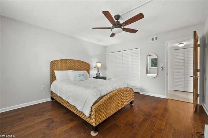 Bedroom featuring dark wood-style floors, a ceiling fan, a closet, and a textured ceiling