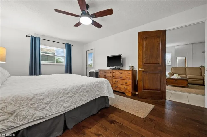 Bedroom with a textured ceiling, dark wood finished floors, and ceiling fan