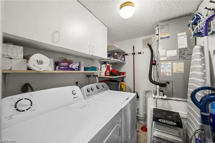 Laundry room featuring a textured ceiling, cabinet space, independent washer and dryer, and heating unit