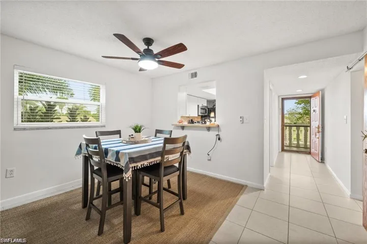Dining room with a textured ceiling, light tile patterned flooring, and a ceiling fan