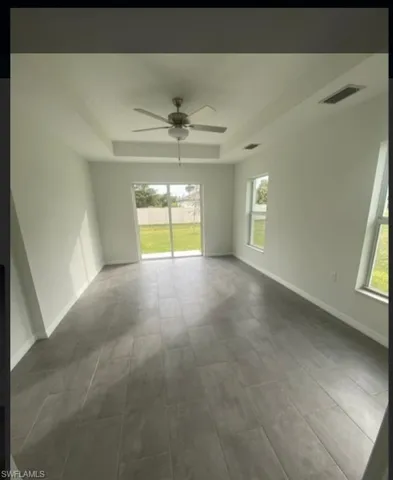 Empty room with a raised ceiling and a ceiling fan