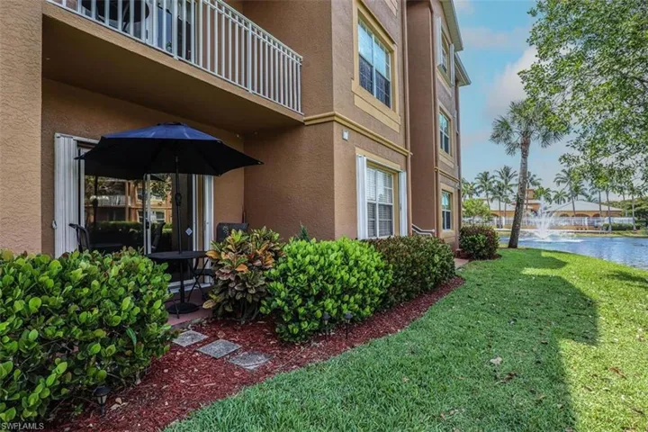 View of side of property with stucco siding, a lawn, a water view, and a balcony