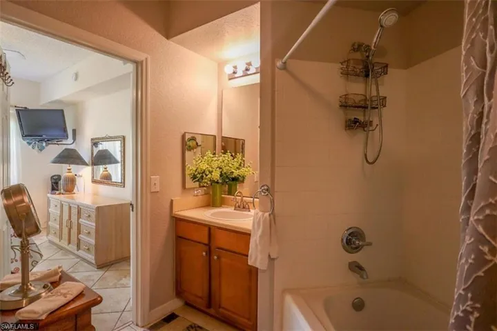 Full bath with shower / bath combo with shower curtain, vanity, and tile patterned flooring