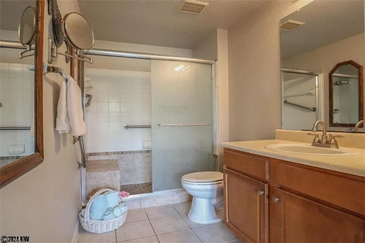 Full bath featuring a shower stall, tile patterned flooring, and vanity