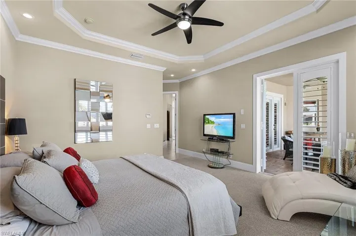 Spacious master bedroom allows for a sitting area and has comfortable Berber carpeting, crown molding, wide baseboard trim, plantation shutters, and French doors leading out to the pool deck.