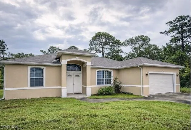 Ranch-style house with a front yard, stucco siding, concrete driveway, and an attached garage