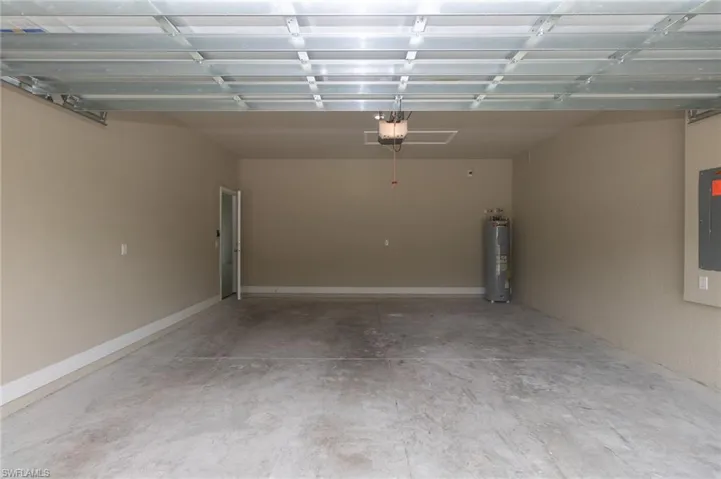 Garage with a garage door opener, water heater, and electric panel