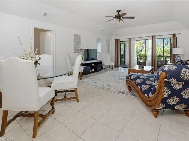 Living area featuring light tile patterned floors, lofted ceiling, and a ceiling fan
