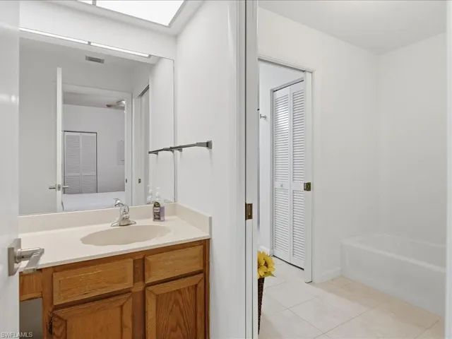 Full bath with vanity, light tile patterned floors, and a closet