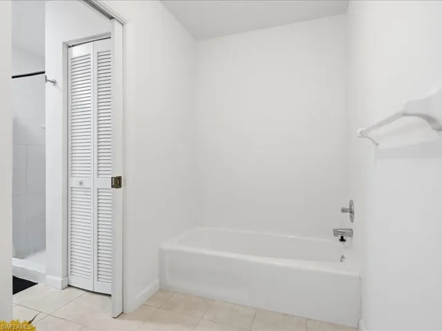Full bathroom with a closet, tiled shower, light tile patterned floors, and a tub to relax in