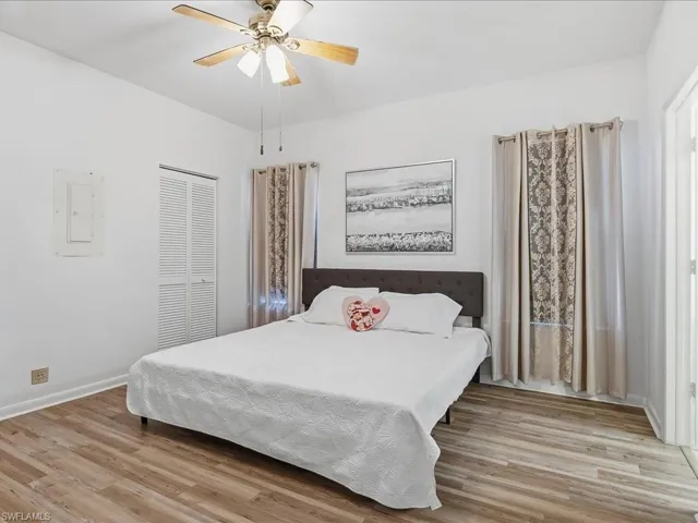 Bedroom with light wood-style floors, electric panel, ceiling fan, and a closet