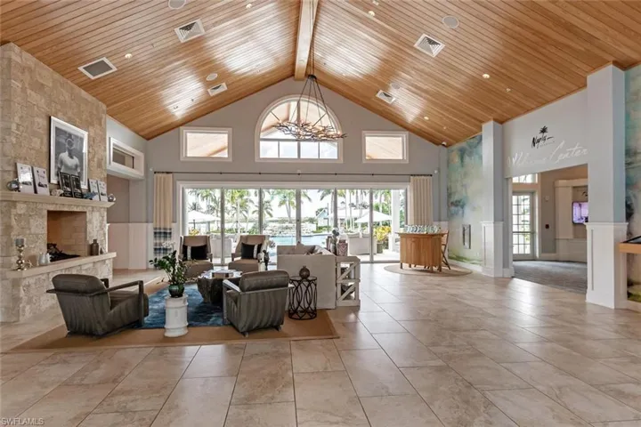 Living room featuring high vaulted ceiling, an inviting chandelier, beamed ceiling, and wooden ceiling