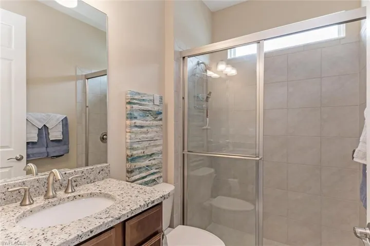 Bathroom with an enclosed shower, toilet, and large vanity