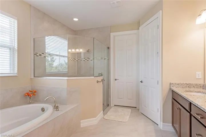 Bathroom featuring tile flooring, separate shower and tub, and vanity