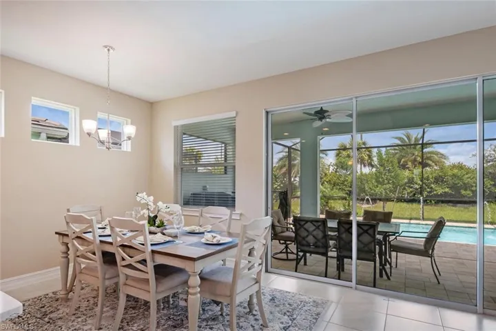Tiled dining space featuring plenty of natural light and ceiling fan with notable chandelier