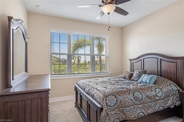 Carpeted bedroom with multiple windows and ceiling fan
