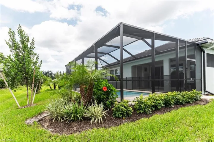 Back of house with glass enclosure and a lawn