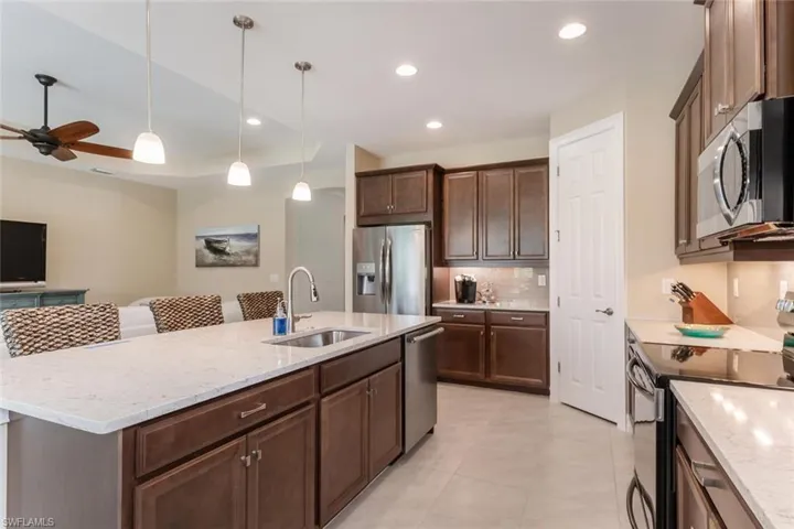 Kitchen featuring stainless steel appliances, a center island with sink, sink, and ceiling fan