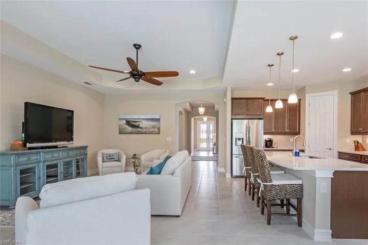 Tiled living room featuring a raised ceiling, ceiling fan, and sink