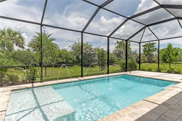 View of pool with a patio, pool water feature, and glass enclosure