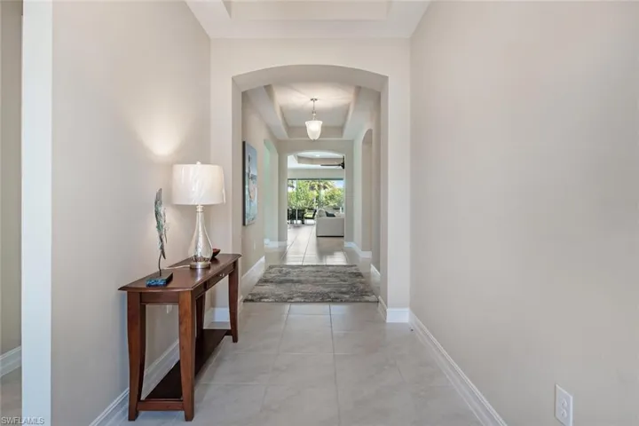 Hallway featuring a tray ceiling and light tile floors
