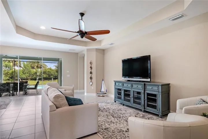 Tiled living room featuring a tray ceiling and ceiling fan