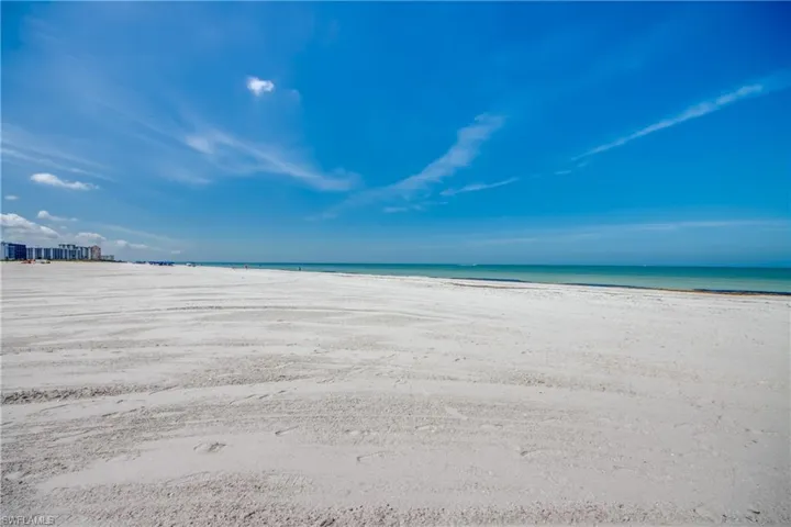 Expansive white sand beach with turquoise waters and a distant skyline