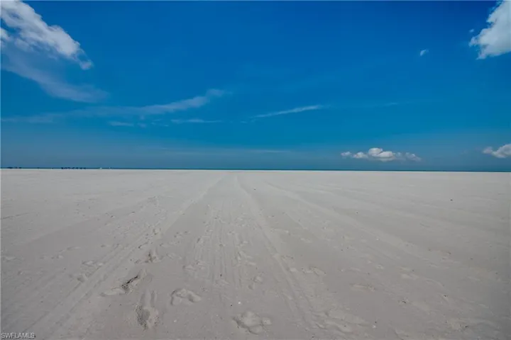 Expansive white sand beach under a clear blue sky with minimal cloud cover
