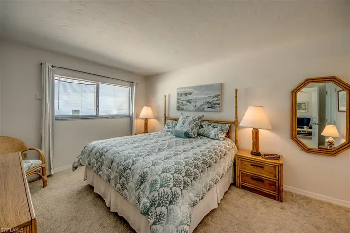 Carpeted bedroom with a window featuring horizontal blinds and white drapes