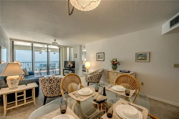 Open-concept living area with a glass dining table and direct balcony access