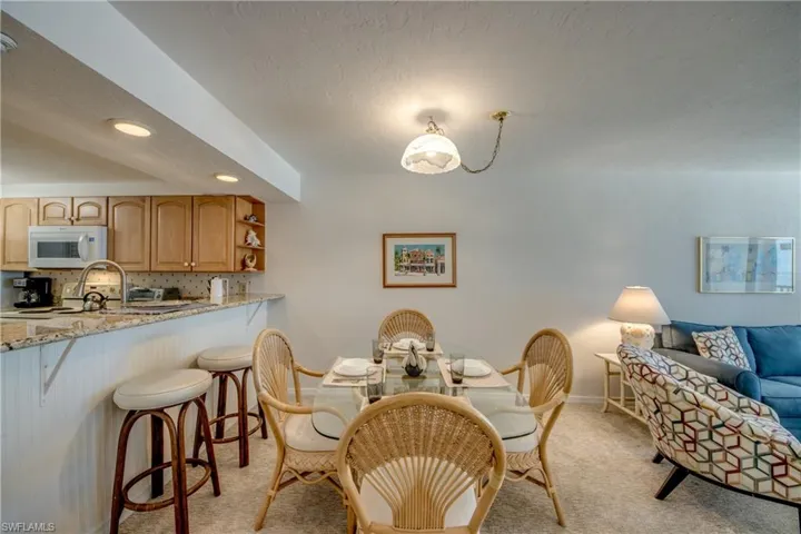Open concept dining area featuring a glass-top table, woven chairs, and a pendant light fixture