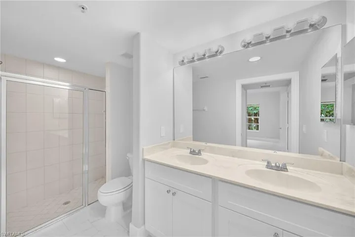 Bathroom featuring walk in shower, tile patterned floors, double sink vanity, and toilet