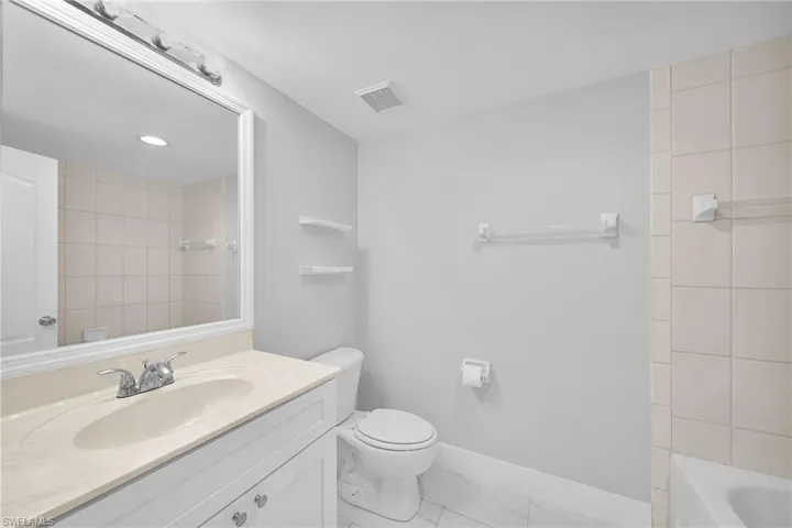 Full bathroom with vanity, tile patterned flooring, tiled shower / bath combo, and toilet